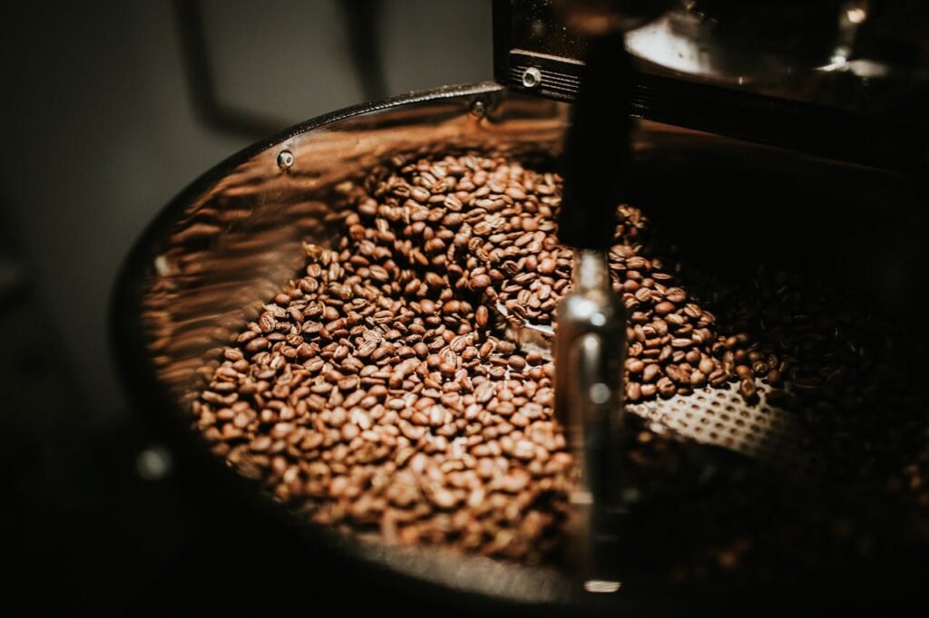 pexels-photo-894695 Close-up of freshly roasted coffee beans in a large industrial coffee roaster, showcasing rich textures and warm tones.